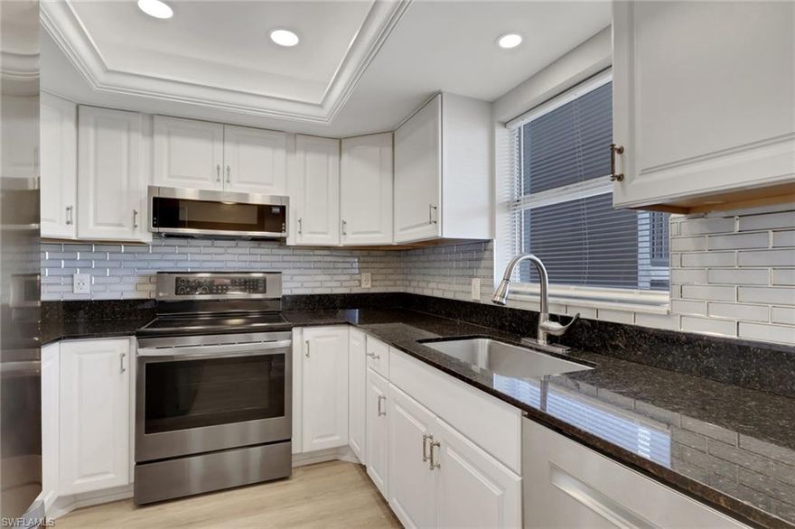 This well appointed two bed/two bath condo has been tastefully updated and is move-in ready. There is newly installed flooring in the living and dining areas, as well as both bathrooms. The kitchen updates include white cabinetry, granite counters, stunning backsplash, stainless steel appliances, and tray ceiling with recessed lighting and crown molding. The bedroom closets are spacious with great storage options. Additional updates include Interior doors/hardware, base trim, lighting fixtures. The rear screened lanai has custom tile and newer washer and dryer. The peaceful view from the lanai includes the lake, beautiful, landscaped area and the golf course. It is a relaxing space to start or end your day, while enjoying the wildlife and the shore birds. There is designated parking in the covered carport next to the building. Country Club Manor is a friendly 55+ community with a large pool, clubhouse and barbeque area just steps from the condo. In addition, the location is very close to the public golf club.  The beaches of Naples and the vibrant downtown are less than 5 miles away!