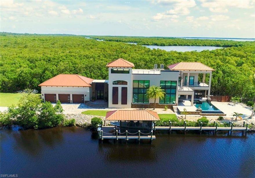 Shown on TV Fox 4 Out and About--This spectacular home is surrounded by preserve, a basin to the bay, and 800' of deep canal. The world is your oyster as boating to the Gulf and nearby islands is a breeze! SHEER LUXURY is available furnished turn-key! Easily a 5 bedroom home, or keep the office and theatre room as they are (both have doors to the hall).  Enter the private gated entry to  800' +/- of paved driveway lined with royal palms.  Two finished garages for 6 cars. Hurricane doors, Impact windows, interior wall sound insulation, solid cherry cabinets, Amish crafted solid core cherry interior doors, Quartz countertops, travertine tile decks, and maple ceilings. Watch the manatees from the lanai with remote-control screens, gas fire feature, pool torches, and cypress ceiling, leading to a Zero edge infinity pool and whirlpool. Outdoor kitchen, pool bath and storage room. Custom boat house and 90' dock includes 8,000 lb boat lift, captain’s walk, steel roof with hardie soffit, Trex decking & more. Custom by Stearns Custom Builders with too many features to describe. No thought was spared for quality, convenience & privacy for this 3-year-old home on a 1.62 acre estate.