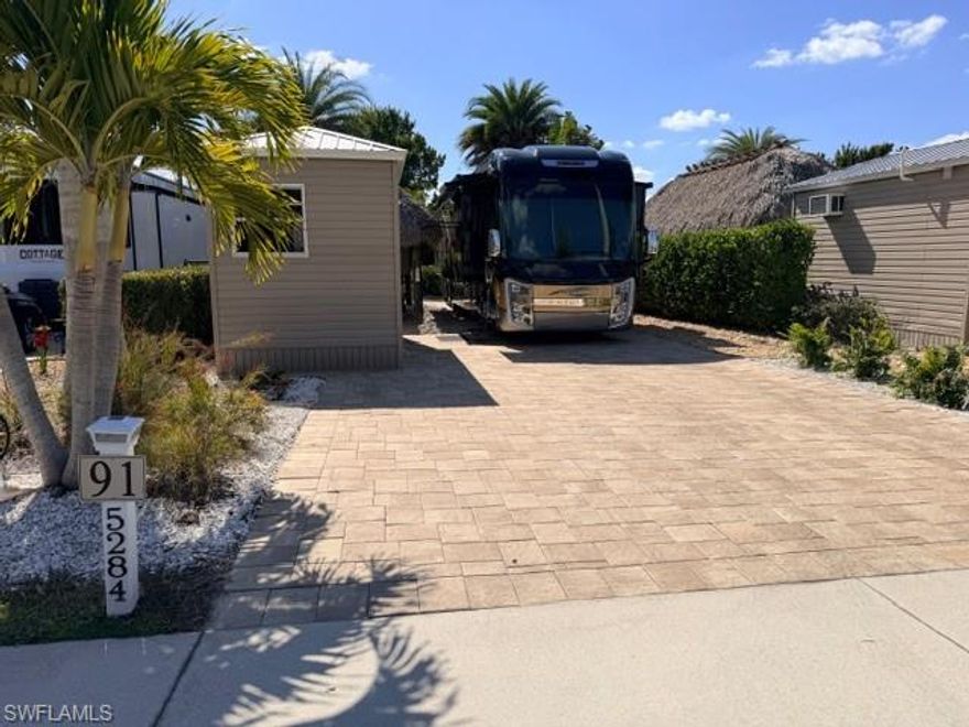 Lot 91 features a fully paved neutral colored north facing lot.  North facing in Florida for many RVs is one of the most preferred positions.  You can enjoy your 10 x 20‘ Tiki Hut with included crank down shades, numerous tiki lights throughout and a pole mounted fan for additional cooling under the Tiki Hut when needed.  In 2021 Amazon placed an 8 x 15‘ unfinished shed which is of course ready for your personal ideas.  The shed features a 100 amp breaker box which feeds electricity to your tiki hut.  There are two large windows, multiple electrical outlets, an overhead light and twin pineapple style outdoor light fixtures.  Fiber optic is already installed in the shed and the unfinished shed is ready for a future shower, toilet, and a sink as it has outside water and sewer pipes right up against the side of the shed.  There is a double door entrance which allows easy access for furniture storage at end of season.  On the property is a fantastic array of plantings outside and alongside the lot that includes manila Palms, rosemary date palms, giant sword, ferns tip plant, Sylvester palms, Areca  palms.  The landscaping includes a variety of seashells upfront and colored stone surrounding the perimeter. Very nice large open green space to the rear.  This is a must see lot so stop in an experience the beauty.