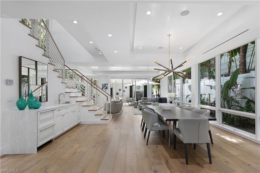 Positioned in the prime section of Olde Naples, this modern coastal cottage by renowned MHK Architecture captures the essence of luxury living—where you can walk to the beach, the boutiques and cafés of 3rd Street South, and the vibrant energy of 5th Avenue South. Thoughtfully designed to blend timeless charm with contemporary elegance, the residence showcases wide-plank white oak flooring, expansive floor-to-ceiling impact glass, and custom ceiling details that create a sunlit, open environment with effortless indoor-to-outdoor flow. The main level features a spacious living room anchored by elegant finishes and a custom-built-in TV console, a dining area with a wet bar appointed with quartz countertops and beverage drawers, and a chef-inspired kitchen with a large LG Signature wine fridge, high-end quartz counters, a center island, custom soft-close cabinetry, and an LG Signature refrigerator. Just off the kitchen, a powder bath complements the wide-open living space, which transitions seamlessly to the private outdoor retreat. Here, a heated pool and spa are framed by pavers, cascading fountains, lush tropical landscaping, and a gas fireplace with mounted TV—all designed for both grand entertaining and quiet evenings at home. The outdoor area has been thoughtfully enhanced with a custom grill, new pool equipment, pool shower, mosquito-repellent misting system, extended paver driveway accommodating nearly three cars, mosquito screen enclosure, artificial turf by the pool, and zoysia grass in the front yard. Bamboo trees complete the space, offering natural beauty and perfect shade for a serene, resort-like setting. The oversized primary suite serves as a private sanctuary, complete with a wet bar, sitting area, Juliet balcony, dual walk-in closets, and a spa-inspired bath with dual vanities, a freestanding soaking tub, and a separate glass shower. Guest suites are equally impressive, generously sized for king beds and offering private baths, while each bathroom throughout the home is finished with natural stone for a refined, spa-like feel. Upstairs, a versatile loft provides endless flexibility—ideal as a fitness studio, office, TV lounge, or creative retreat. Additional highlights include: a car lift in the garage, designer light fixtures throughout, a whole-home Sonos sound system, a new security system, full impact-rated windows and doors, a smart-home system with phone-controlled automation, app-enabled AC controls, and a kitchen water filtration faucet. Blending Olde Naples charm with modern sophistication, this exceptional residence offers an unmatched combination of location, design, and lifestyle.