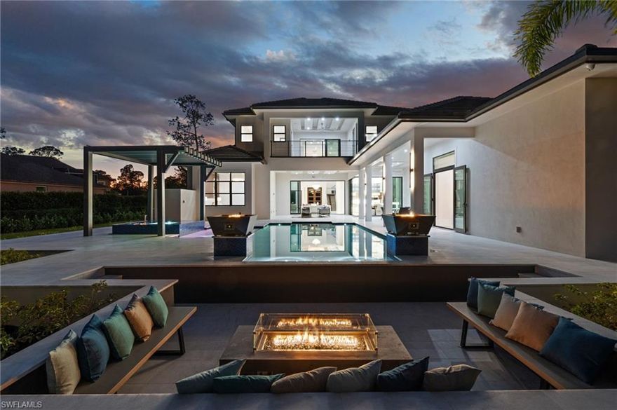 Discover an extraordinary new-construction estate, poised on over two acres in the prestigious Oakes Estates community. This private gated sanctuary offers more than 5,411 square feet of air-conditioned living space and approximately 10,000 total square feet, delivering the perfect blend of seclusion, sophistication, and masterful craftsmanship. Thoughtfully designed for the discerning buyer, the residence features six spacious bedrooms, each with its own private ensuite, ensuring exceptional comfort for family and guests alike. The home boasts four kitchens—including a show stopping gourmet chef’s kitchen, a fully equipped butler’s kitchen, and a luxurious outdoor kitchen—creating an unmatched environment for both daily living and large-scale entertaining.
Every detail reflects an unwavering commitment to quality. The kitchen is outfitted with elite appliances such as a Wolf range, Sub-Zero and Cove refrigeration, and Bosch systems, all complemented by stunning Crystallo Quartzite waterfall countertops. Throughout the home and outdoor living spaces, the builder has crafted custom handmade inverted masterpiece ceilings, beautifully accented with both uplighting and downlighting to create a dramatic, high-end ambiance. Furnished by Robb & Stucky. A private poolside casita (548 Sq ft) offering an additional full kitchen, living room, bedroom, and bathroom—an ideal retreat for guests or extnded family seeking complete independence.
The interior exudes luxury at every turn, showcasing two expansive living areas, a dedicated office, and a striking glass staircase. Soaring 12.5-foot ceilings enhance the main living spaces, while a breathtaking 25-foot ceiling in the grand foyer makes an unforgettable first impression. Contemporary water vapor fireplace provides the visual sophistication of traditional fireplaces while offering a serene, maintenance-free experience indoors and outdoors.
The resort-style outdoor oasis includes a stunning pool and spa, beautiful water features, fire-bowls, a built-in fire-pit seating area, hurricane-impact windows and doors, and an impressive 25 kW generator to ensure uninterrupted comfort. Additional conveniences include three separate laundry rooms—upstairs, downstairs, and in the casita—along with a four-car garage, elevator, and expansive outdoor living spaces designed for both entertaining and quiet relaxation. The primary suite is conveniently located on the main level. Perfect for the luxury buyer who demands the very best, this estate offers unparalleled elegance, privacy, and craftsmanship in one of Naples’ most sought-after neighborhoods. This home is perfect for a large family that loves to entertain.