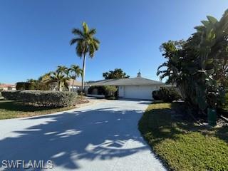 Single-family home in Palm River Estates, featuring a paved driveway, tropical landscaping with palm trees, and a clear blue sky.