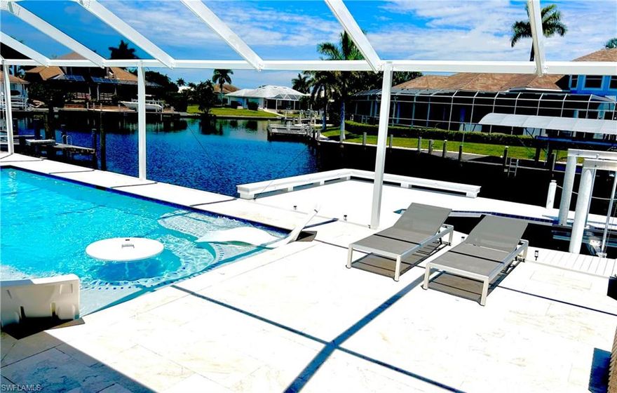 Experience true Marco Island living in this beautifully updated waterfront home, offering modern upgrades, expansive outdoor space, and stunning wide water views. Situated at the end of a quiet cul-de-sac, the property features a brand-new 111-foot seawall with a 25-year transferable warranty, along with a custom-built 800+ sq ft dock accommodating up to a 32-foot boat. A new 16,000 lb boat lift is also included, all with transferable warranties—perfect for boating enthusiasts. The home boasts a spacious, light-filled interior with fully retractable patio doors that seamlessly blend indoor and outdoor living. The large screened-in pool area with covered panoramic enclosure provides the ideal setting for relaxing or entertaining while enjoying serene water views. The modern kitchen is equipped with sleek cabinetry, black granite countertops, built-in oven and cooktop, and high-end appliances, including a Bosch integrated, ultra-quiet dishwasher. The dining area is perfectly positioned to take full advantage of the waterfront scenery. All bedrooms are generously sized with large windows that fill the space with natural light, many offering water views. The primary suite features a luxurious bathroom with a double walk-in shower with multiple shower heads, soaking tub, dual vanities, and contemporary finishes, along with a dedicated dressing area. The guest bathroom has also been tastefully updated. Additional upgrades include impact-rated Low-E windows (2021), a new roof and gutters (2018), new pool, deck, and lanai (2019), multi-split A/C system (2023), water heater (2020), pool heater (2025), and a newly paved driveway and patio (2026). The two-car garage includes a large hidden storage area behind stylish barn doors. This exceptional property combines modern comfort, quality upgrades, and prime waterfront living in one of Southwest Florida’s most desirable locations.