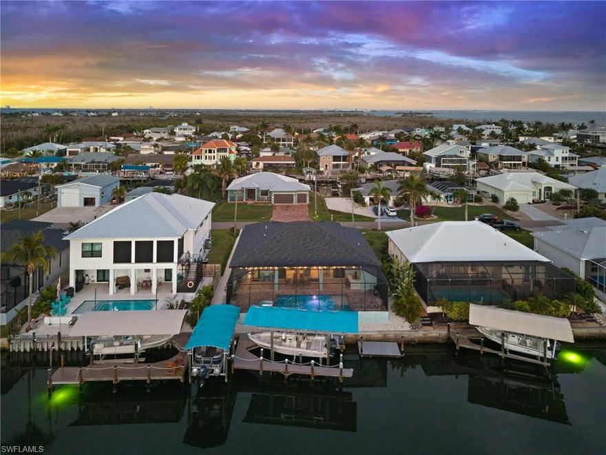 Experience the pinnacle of Southwest Florida waterfront living in this stunning 2024 new construction residence, where modern luxury meets effortless coastal elegance. Thoughtfully designed with both sophistication and versatility in mind, this expansive home offers 5 bedrooms, 3 full baths, including two private primary suites, along with two additional flex spaces perfect for a home office, den, or guest overflow. Step inside to a light-filled great room featuring a desirable split-bedroom floor plan and elegant coffered ceilings, creating the ideal balance of openness and privacy. The chef-inspired kitchen is the heart of the home, showcasing 42” upper cabinetry, stainless steel appliances, a large center island designed for gathering, complemented by a dedicated entertaining bar with a built-in beverage refrigerator. The primary suite is a true retreat with two walk-in closets, a spa-like bath featuring dual vanities, a walk-in shower, and a spacious linen closet, while sliding glass doors open to the lanai and tranquil water views. A second private primary suite offers exceptional flexibility for guests or multi-generational living and includes a walk-in shower with convenient access as a pool bath. Outdoor living takes center stage with a spacious lanai and a stunning saltwater pool and spa, featuring electric heat, LED lighting, and a tranquil waterfall feature from the spa into the pool. Western exposure sets the stage for breathtaking sunset views, while ample space allows for the future addition of a custom outdoor kitchen—perfect for elevating your entertaining experience. A true boater’s paradise, this exceptional waterfront setting offers a premier dockage experience with two covered lifts, a low-maintenance composite dock, captain’s walk, and a versatile floating dock, all equipped with water and electric. With quick, direct deep-water access to the bayfront and the renowned fishing grounds of Pine Island Sound, and with Sanibel, Captiva, Cayo Costa, and Boca Grande beaches just a short boat ride away, this location delivers the ultimate coastal experience. Built for both beauty and peace of mind with impact windows and doors and a spacious 3-car garage, this home offers the perfect blend of luxury and function. Beyond the property, embrace the charm of Pine Island’s laid-back lifestyle, where golf cart-friendly streets lead you to local restaurants, marinas, and waterfront favorites, and each day ends with breathtaking sunsets and the unmistakable rhythm of true island living.