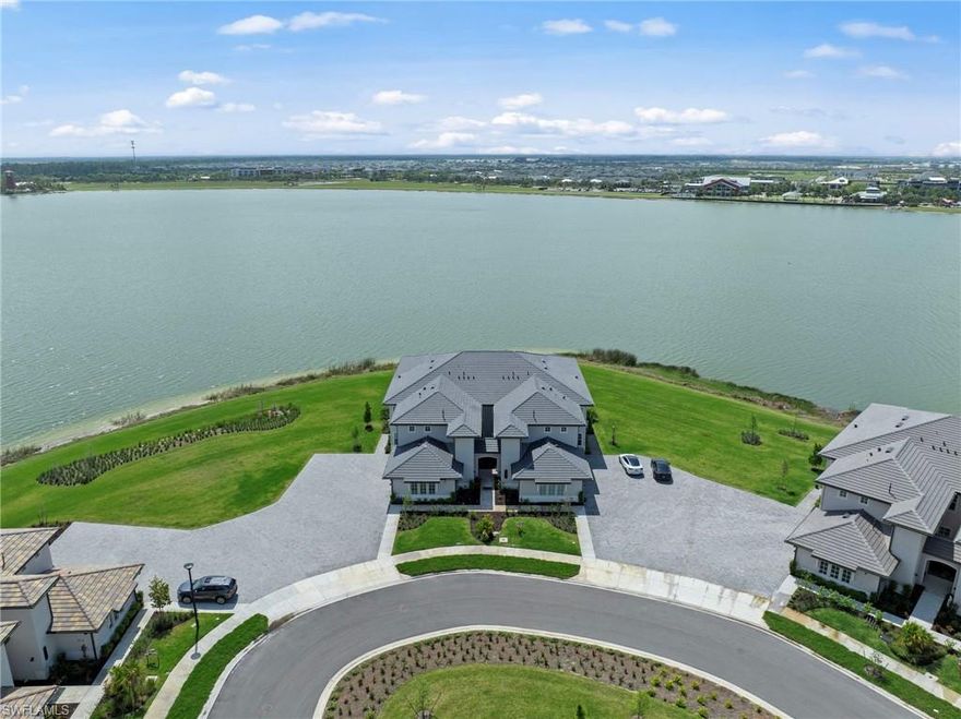 Absolutely stunning coach home on a peninsula lot with expansive panoramic views over Lake Babcock. Perfectly positioned on a quiet cul-de-sac , this ground level, walk-out residence offers rare privacy with no direct neighbors. Recently built and offered furnished, the home shows like new and features a bright, open-concept layout with abundant natural light. The views take center stage, through the large panel sliding glass doors framing the water from the main living areas. The floor plan includes three bedrooms and two baths, with a split layout that works equally well for owners and guests. The kitchen is modern with quartz countertops, shaker-style cabinetry, and stainless steel appliances, natural gas range, all flowing seamlessly into the living and dining areas. Step out to the screened lanai and take in the wide lake views.. Additional features include impact windows and doors, a two-car garage, and meticulous, like-new condition throughout. Located close to Founders Square with easy access to community amenities, dining, and walking trails—this is a standout opportunity in one of the best spots on Lake Babcock.