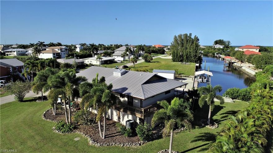 Rare THREE LOT SITE with GULF access & NO BRIDGES in Pirate Harbor. Casual coastal design w/ 5196 Sq Ft of living space w/ areas under air totaling 2568 Sq Ft. “Captains Quarters” on level two consists of a large great room (living/dining/kitchen) w/ soaring 11' wood vaulted ceilings + 3 bedrooms & 2 baths. Living & Dining areas open to Kitchen featuring wood cabinetry & granite countertops /w tin backsplash & stainless floating hood. Master suite & two additional bedrooms upstairs all have beautiful pine wood flooring. Lower level offers GUEST HOUSING w/ PRIVACY. 1 bed/1 bath suite w/ living/kitchen/dining & storage space + fitness room & screened lanai access. Spectacular outdoor living spaces including covered upper & lower lanais + wrap around porch. Over 100' of newer concrete seawall w/ 57' tiered dock + covered boat lift. Additional outdoor features include a fenced area for pets & 12x24 shed/work shop built in 2020. Attached 2 car garage + RV parking w/ 50, 30 & 20 amp service. PRIVATE boat ramp for easy entry in & out of the water. Lusciously landscaped, palms & tropical species add to the island feeling you are sure to enjoy, in the place the locals call PARADISE.