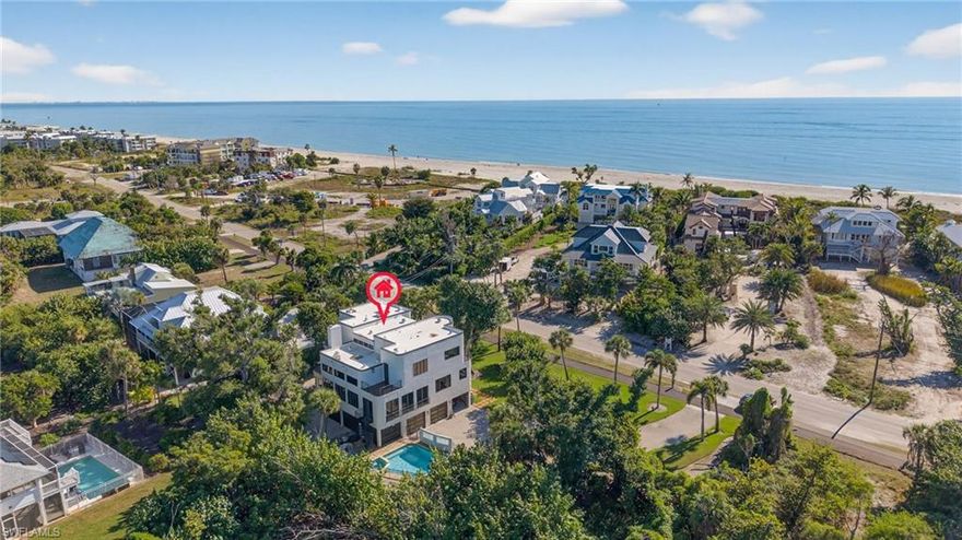 Located along the highly desirable West Gulf Drive corridor, this tri-level, 4 bedroom, 3.5 bath home offers an exceptional opportunity to enjoy refined island living on over half an acre of land directly across the street from the beach. This spectacular property spans 3,994 sq feet and showcases a striking contemporary design with distinctive art deco lines, defined by massive geometric forms, curving expanses of glass block, rounded corners, and an impressive six balconies and decks—creating a home that is both architecturally bold and uniquely coastal. The thoughtfully designed floor plan features expansive, light-filled interiors and open living spaces ideal for entertaining or everyday comfort. At the heart of the home, a gourmet kitchen anchors the main living area, offering a functional yet elegant space for hosting, and daily living. All impact windows and doors provide peace of mind, enhanced storm protection, and energy efficiency, while modern finishes and architectural details elevate the home’s sophisticated yet welcoming feel. The tri-level layout allows for excellent separation of space, with generous bedroom accommodations offering privacy and flexibility for family and guests. Outdoor living is a true highlight, featuring a screened lanai porch overlooking a private pool and spa. Adding exceptional functionality, the property includes a 3-car garage along with a large lower-level storage area, ideal for bikes, kayaks, beach gear, and island essentials. Deeded beach access places Sanibel’s white-sand shoreline just moments away, while the across-the-street beach location allows for effortless days of shelling, sunset walks, and coastal living. Set in one of Sanibel’s most sought-after locations, this residence offers convenient access to scenic bike paths, renowned dining, and the island’s natural beauty, all while maintaining a tranquil and private setting.