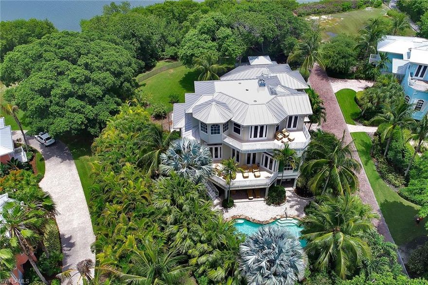 Nestled among the emerald green waters of fascinating Captiva Island, you will find the community of Tarpon Bay. This gated community offers Gulf and bay living at its very finest, where you truly have the best of both worlds. There is deeded beach access for shell-seekers and Bayfront living for boat enthusiasts, offering direct gulf access via Pine Island Sound. This Key West-style home with an attached guest house has all the fine amenities expected from a home of this caliber. In addition to the many upgrades, this home offers a private elevator, a stand-alone art studio, an air-conditioned garage and a generator system. The resort-style pool with a cascading spa and outdoor kitchen make for easy and elegant entertaining. This home is situated on a one-acre homesite, offering a tranquil park-like setting.