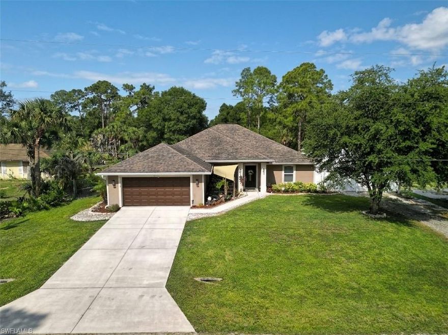 This custom built 2015 home offers 4 bedrooms and over 2000 square feet on a fenced half acre lot, complete with impact windows and sliding glass doors, with no HOA, no flood zone, and no restrictions telling you how to live. The setting is quiet without feeling remote, with shopping, dining, medical facilities, and Lehigh Community Park just minutes away. A welcoming front porch with a koi pond sets the tone, while a full irrigation system keeps the landscaping looking lush. Gutters wrap the entire home, a feature many new construction homes simply no longer include. Out back, the space is set up for both relaxing and everyday living, with a saltwater pool featuring a half moon shelf and water feature, a firepit area, and plenty of room for kids and pets to play or even start a garden. An RV hookup and EV charging add convenience without sacrificing space. Inside, cathedral ceilings and a split floor plan create an open yet functional layout. Wood flooring runs through the main living areas, with tile in the kitchen and baths. A new tankless water heater adds efficiency. The kitchen is finished with granite counters, a walk in pantry, and quality cabinetry, all flowing easily into the main living space. The primary suite is privately positioned and offers a spacious ensuite with double sinks, a large walk in shower with a rain shower head, and a huge walk in closet with custom built ins. The additional bedrooms are comfortable in size and share a second bath with double sinks that also serves as the pool bath, giving easy access for guests and outdoor use. Even the garage has been freshly painted, adding to the clean, well cared for feel of the home.