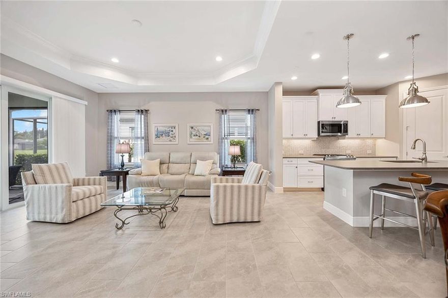 Located in Marquesa Isles, this two-bedroom plus den residence blends timeless design with modern upgrades. The foyer opens to 9-foot ceilings, 8-foot doors and 24-by-12-inch ceramic tile flooring in the main living areas. Glass French doors lead to an 11-by-12-foot den, suitable for a home office, reading space or guest accommodations. The open kitchen features an oversized quartz island, G.E. stainless steel appliances, designer tile backsplash, 42-inch cabinetry with crown molding and under-cabinet lighting. The 16-by-17-foot great room includes a coffered ceiling with crown molding and southern exposure lake views. The primary suite includes a walk-in closet, additional closet, and an en-suite bath with dual sinks and an oversized, designer-tiled shower. The screened lanai spans 14-by-10 feet with a 10-foot extension and sunshade, overlooking the lake. Additional features include impact pocket sliding doors, plush bedroom carpeting, custom window treatments, Smart Hub integration with Z-wave devices, Hotwire fiber-optic service, and an 18-by-20-foot garage with epoxy floor, insulated door and attic insulation. Marquesa Isles amenities include a clubhouse, resort-style pool and hot tub, dog park and landscaped grounds, all within a gated community close to Naples shopping, golf and beaches.