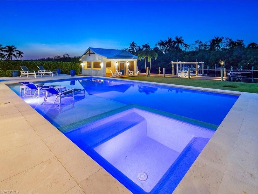 Prepare to be captivated by this exceptional waterfront residence, custom built by JVM and located in one of Naples’ most desirable communities — notably with no flooding or storm damage from recent hurricanes. This beautifully designed one-story home showcases a seamless blend of timeless craftsmanship and modern luxury. The open-concept great room floor plan is flooded with natural light and offers stunning water views throughout. Soaring volume ceilings with elegant wood beam accents, wide-plank engineered hardwood flooring, and sophisticated finishes set the tone for effortless coastal living. The heart of the home is the chef’s kitchen, featuring a 12-foot quartz island, Viking stainless steel appliances, a gas range, farmhouse sink, pristine white cabinetry, and a spacious walk-in pantry. A walk-through butler’s pantry—with second refrigerator, laundry area, sink, and custom cabinetry—adds both convenience and charm. With three generously sized bedrooms, a private den, and four impeccably appointed full baths, the layout offers comfort, style, and flexibility. Step outside to a true waterfront oasis: a saltwater pool, oversized spa, sun shelf, and a screened-in covered boathouse create the ultimate backdrop for relaxation or entertaining. A private dock with 15,000 lb lift, water and electric, provides quick Gulf access and puts downtown Naples, Keewaydin Island, and Marco Island just minutes away by boat. Additional highlights include a spacious three-car garage, 30- and 50-amp service ideal for generators or EV charging, and a rare combination of location, protection, and premium finishes. This is coastal living at its finest—schedule your private showing today.
