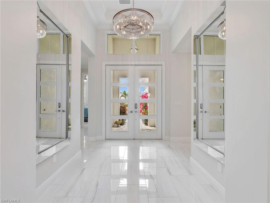 This exceptional lakefront residence blends luxury design, high end upgrades, and true indoor outdoor Florida living. This beautifully appointed home offers 3 bedrooms plus a finished office, 3 full bathrooms, and an extended 2 car garage, all thoughtfully designed with comfort and functionality in mind. From the moment you arrive, the upgraded glass front door, enhanced landscaping, and elegant foyer millwork set the tone for the quality found throughout. Inside, the home features 16 x 32 porcelain marble tile flooring throughout with no carpet, complemented by tray ceilings, crown molding, and solid core doors that elevate the overall aesthetic. Plantation shutters and upgraded lighting fixtures in the foyer, dining room, kitchen island, primary suite, and porch create a polished and cohesive look. The designer kitchen has been extended to maximize both space and usability, showcasing upgraded cabinetry with under cabinet lighting and electric, upper glass cabinets with display lighting, a stainless steel farmhouse sink, reverse osmosis system, and premium KitchenAid appliances. A built in beverage refrigerator adds convenience, making this kitchen perfect for entertaining. The primary suite is a private retreat featuring dual California closets, direct access to the lanai, and a spa inspired bathroom with an oversized walk in shower complete with an additional rain shower head and upgraded glass enclosure. All three bathrooms feature upgraded sinks, toilets, and glass enclosures for a refined finish. Step outside to your private lakeview oasis, where a fully automated saltwater pool and spa takes center stage. The pool system can be controlled directly from your phone and is equipped with both a natural gas heater and an efficient heat pump for year round enjoyment. The expansive lanai includes an outdoor kitchen with hood, ceiling fans, hurricane screens to secure patio furnishings, and a No See Um screened cage for added comfort. Additional highlights include hurricane rated 10 foot sliding glass doors, a glass office entry door, Amish built cabinetry with quartz countertops in the office and laundry room, a pocket laundry door, upgraded washer and dryer, and a comprehensive security system with exterior WiFi cameras. Practical upgrades such as an A C soft start, 240V generator plug, overhead garage storage, and automatic garden hose reels on both sides of the home further enhance convenience. Situated on a premium lakeview lot, this home offers a rare combination of luxury finishes, thoughtful upgrades, and serene water views, delivering the ultimate Naples lifestyle.