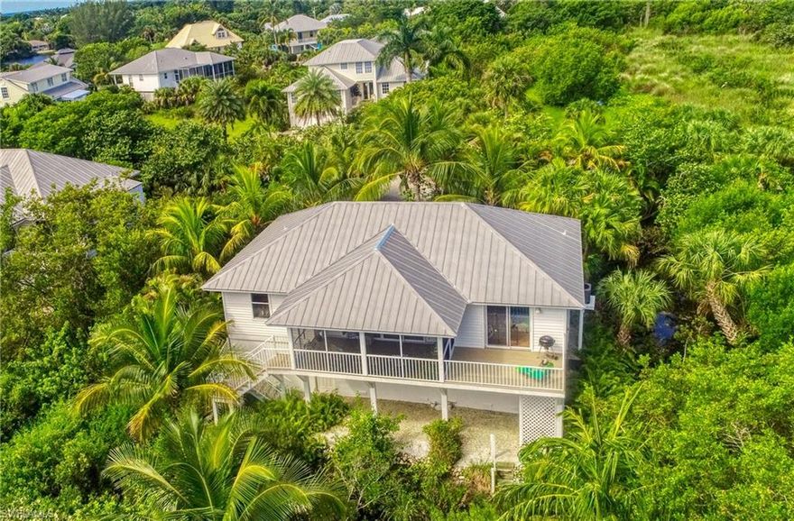 Your piece of paradise. Private. Quiet. Walking and biking distance to your deeded beach access on West Gulf Drive. Surrounded by a National Wildlife Refuge with no through-traffic, the view of your secluded setting includes mature palm trees as well as the natural environment. Vaulted ceilings and great room open to a covered screened lanai facing east that overlooks preservation land. Ideal split floor plan affords privacy to all. The master suite, with its own sundeck, offers a beautiful view of the sunrise. Spectacular sunsets can be viewed from your covered front porch & your living room. The spacious kitchen features granite countertops with a tumbled marble backsplash, granite sinks and a large center island. Additional features of this home include a metal roof, a new AC system in September 2021, interior crown molding throughout, laundry room and a fully enclosed two-car garage with substantial storage including built-in shelves and work benches. The downstairs back porch hosts a shell-washing station with running water and an outdoor shower. If you have been seeking the ultimate Florida home in a private near beach setting, you have arrived.