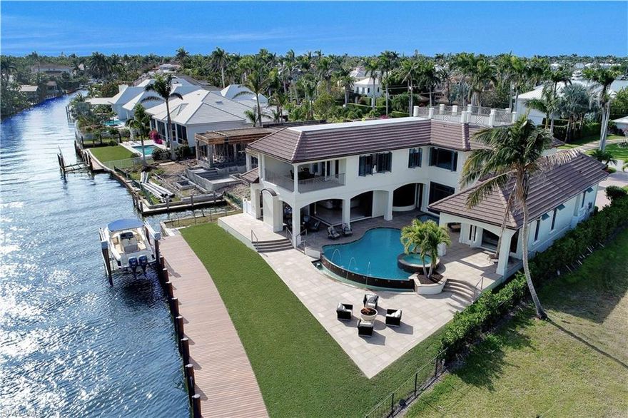 H.12856 - AMAZING BOATERS VIEWS from every room noticed immediately upon entering from large picture window! An oversized home-site allows expansive rooms - family room flaunts 10’ sliders & disappearing plantation shutters open onto oversized deck bringing the outdoors in (approx 150’ from Naples Bay!) w/ 2 fireplaces, lanai grill area, TV/dining area, electric screens, vanishing edge pool w/ streaming fountains & LED colored lighting, spa + firepit gathering area in addition to green yard space. S, E & W views amongst swaying palms! Master suite (w/Jacuzzi tub, his/hers water closets & bidet) + 1 BR downstairs. Upstairs touts 2 BR’s + den, mini kitchen, bonus leisure room w/lg balcony all w/ glorious views of the Yacht Club and Bay (2nd floor is solid concrete block construction!) A 3 ½ car garage has high ceilings expandable to 6 cars or storage via future lifts. Elevator, 500 gal. propane gas, large circle drive, 1 touch lighting, central vacuum & security system. Island kitchen w/gas cooking, Viking appliances + lg dinette & breakfast bar w/ BAY VIEWS. NEW SEAWALL, DOCK & LIFT! Cycle, jog or walk to delightful 3rd Street dining, shopping, galleries & white sand beaches nearby!