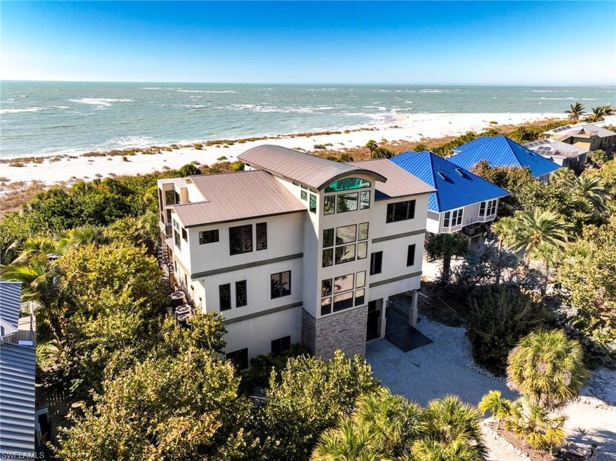 Beauty & The Beach is one of the most extraordinary Gulf-front estate homes ever offered for sale on North Captiva Island! This custom-crafted contemporary residence sits on the central portion of the island's widest stretch of beach, providing greater long-term shoreline security and uninterrupted panoramic Gulf views.
A proven luxury vacation rental leader, this home generated over $360k in gross rentals in 2021.  The property booked over $250k in gross rentals in 2025, even with downtime for repairs and upgrades.  This is a rare opportunity to acquire both a premier vacation retreat and a top-tier rental asset.
Designed with a striking stucco exterior, impact-resistant glass throughout, and a private interior elevator serving all three levels, the home delivers refined coastal architecture paired with modern convenience. The ground-level area provides a bonus room & bunk area, plus an extensive outdoor entertainment space with a pool, patio, outdoor kitchen & poolside bar, all connected by a private walkway to the island's most pristine sugar-sand beach.
Inside, every space is meticulously planned & designed for elevated entertaining & relaxed luxury. Highlights include a gourmet chef's kitchen, a dramatic dining room crowned by soaring barrel-vaulted ceilings, and a formal living area wrapped in panoramic glass. A built-in fireplace with television above the hearth anchors the living space with warmth and elegance.  The two primary living levels were designed to capture the spectacular Gulf and sunset views.  
The 4 elegant bedroom suites provide marvelous spaces for you and your guests to experience five-star resort-style luxury sleeping accommodations.
The top-level primary suite boasts panoramic beach views, an en suite bath with a walk-in shower, a dual-sink vanity, and a lockable owners' closet.  Imagine relaxing in the extra-deep soaking tub while you stare at the shimmering waters lapping the shoreline. The second primary suite, located just off the entertainment den/media room, offers excellent beach views & a luxury en suite bath with a walk-in shower. Two more north-facing guest suites create "family-suite-style" guest zones with a Gulf-facing King bed suite & en suite bath, plus an adjacent bedroom & bath.  Opportunities to acquire a Gulf-front estate of this caliber, location, and proven income performance are exceedingly rare on North Captiva Island. Beauty & The Beach represents the very best of luxury island living!