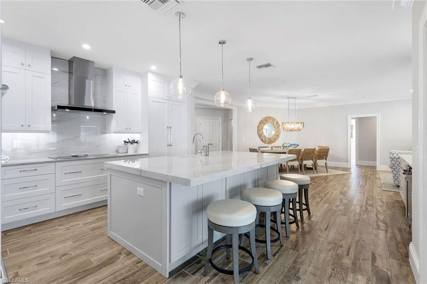 This beautifully renovated residence offers a polished coastal aesthetic just moments from Naples’ renowned white-sand Gulf beaches. Surrounded by pristine, manicured landscaping, the property features automatic irrigation, landscape lighting, and a fully fenced yard—ideal for privacy, pets, and relaxed outdoor living. At the heart of the home, the open-concept living, dining, and kitchen areas create an inviting, free-flowing space designed for both entertaining and everyday comfort. Wide ceramic plank tile runs throughout, while the thoughtfully designed kitchen showcases JennAir appliances, an induction cooktop, a generous quartz island, custom white shaker cabinetry, under-cabinet lighting, and a pullout pantry for added convenience. Just beyond, a sleek wet bar with a wine cooler, ice maker, and filtration system enhances the property's hosting potential. Outdoor living takes center stage on the travertine lanai, finished with shiplap ceilings and recessed lighting for a warm, coastal feel. The heated gas pool—powered by a 1,000-gallon propane tank—anchors the space, complemented by a fully equipped outdoor kitchen with a Big Green Egg, built-in grill, refrigerator, granite bar, and a quartz pass-through to the interior wet bar. The primary suite is a peaceful retreat, accented by wood ceiling details, crown molding, and soft recessed lighting. Its spa-inspired bath features a freestanding soaking tub, walk-in shower, dual quartz vanities, and marble flooring, along with a custom walk-in closet. Each guest suite offers its own updated en-suite bath with quartz finishes and walk-in showers, and an additional full bath adds extra flexibility for visitors. Additional highlights include a 2018 roof, 2022 air-conditioning system, impact-resistant doors and windows, and a full surveillance setup. The two-car garage is finished with epoxy flooring and hurricane-rated doors for added durability and peace of mind. Residents have the option to join the Park Shore Association, granting access to the private beach, dedicated parking, a scenic walking trail, and a barbecue area. With its refined updates, inviting outdoor spaces, and prime location, this Park Shore home delivers an effortless Naples lifestyle.