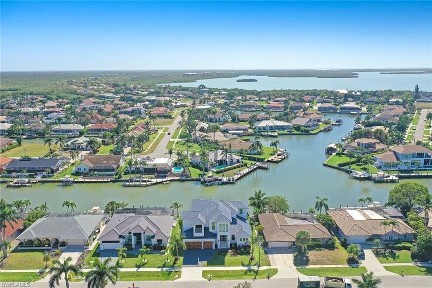 Brand New Build with Captivating Water Views Awaits! Step into an upscale coastal contemporary lifestyle with this stunning 2-story home boasting 4 Beds, 5 Baths and 5559SF TTL. Expansive water vistas take in converging waterways throughout the residence.The open-plan living area welcomes you with soaring ceilings adorned with 12-foot tongue and groove wood lining, accentuated by an abundance of sliders that invite natural light. Refined elegance with sophisticated fixtures, designer lighting and luxurious finishes along with exceptional architectural details define modern sophistication. With meticulous attention to detail, this home boasts wide wood plank flooring, Quartz and stone counters, bespoke tile work, and designer wall finishes. The gourmet kitchen with pristine white oak drawers and cabinets, an expansive gas cooktop/range, and a spacious island includes a breakfast bar and wine fridge. A stylish walk-in butler's pantry, features a wet bar with refrigerator which adds an extra layer of convenience for entertaining. The ultimate outdoor oasis is complete with a covered summer kitchen and dining area boasting a built-in grill, ice machine, and fridge, accompanied by a cozy gas fireplace in the living area for al fresco lounging and dining under the stars. Electric drop-down screens and hurricane shutters, along with impact glass throughout, ensure both comfort and security. Retreat to the sumptuous ground floor primary suite, where panoramic water views await and Indulge in luxury with dual custom-built walk-in closets and a spa-like marble-lined bath featuring a large free-standing tub, zero-entry shower with bench, dual sinks and designer lighting. Upstairs, three generously proportioned ensuite bedrooms await, each offering its own unique charm and character. Gather in the shared living space with wet bar, or step out onto the open terraces to revel in the scenic waterfront. Outside, the southeast-facing open water rear views flood the home with natural light, while the Travertine pool decking leads the way to the zero-edge shallow beach pool and spa with pool bath. The fenced yard, complete with a lush lawn, extends to the dock with lift and newer (2020) seawall, perfect for water direct (no bridges), boating to the Gulf. Additional features include two separately zoned A/C systems, comprehensive home security features for added peace of mind and a 3 car garage. Paradise awaits in this contemporary coastal NEW BUILD masterpiece, offering a new chapter in luxurious Florida living.