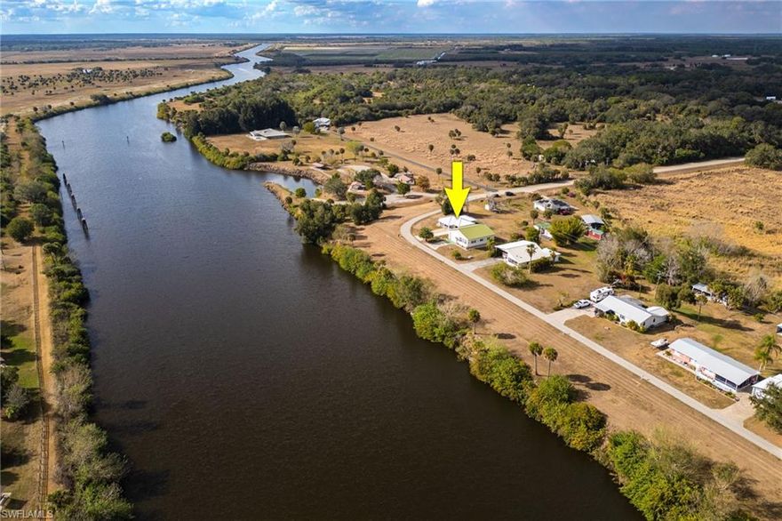 Enjoy beautiful Caloosahatchee River views from your living room and front porch, with convenient access to the nearby boat ramp—without the expense of riverfront ownership. Built in 2021, this home features oversized tile flooring, a metal roof, and upgraded impact windows and doors, all designed to maximize comfort, durability, and the spectacular water views. Located on a spacious corner .46+/- acre lot, in the Ortona community, just a short walk to the Ortona Locks, fishing dock and boat ramp.