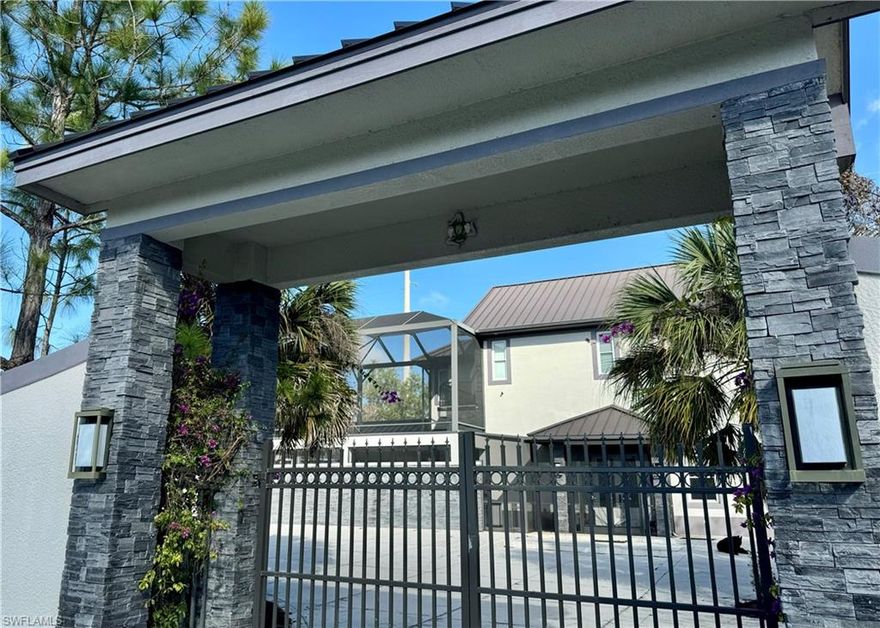 This spectacular custom-built residence in Golden Gate Estates sits on 1.66 acres and offers three bedrooms, three -and -a-half bathrooms, with a thoughtfully designed two-level layout. The home showcases extensive custom stonework throughout, enhanced by natural light from skylights and convenient elevator access to the second floor. An oversized three car air-conditioned garage with epoxy flooring adds both function and luxury. Attached to garage is a private home office. The chef's kitchen features a gas stove and a custom island designed with pass-thru extra storage. Also featured is a long breakfast bar and tons of cabinet space. There are electric custom roll-up shades throughout the home as well. Both upstairs bedrooms enjoy privately screened balconies, creating serene retreats with peaceful views. Brand new Publix grocery just minutes away by car.
 Designed for both beauty and durability, the property features a metal roof rated to withstand up to 180mph winds and is enclosed by an eight foot reinforced concrete wall with impressive stone-accented front gates. Backyard features a children's two story custom playhouse . Also included is a 500 gallon propane tank for patio grilling and all gas appliances. Outdoor living shines with a waterfall spa, travertine marble patios, room for a pool, and fruit trees . Inside the home is a temperature-controlled custom wine cellar to accommodate up to 800 bottles with a handcrafted entry door. This cellar could also serve as a safe room for storms. There is custom tile work and inserts in all three bathrooms, some with  floating shelves. The primary suite offers a California-style-closet with custom shelving and natural skylight, completing this one of a kind luxury estate. Custom crown moulding throughout.