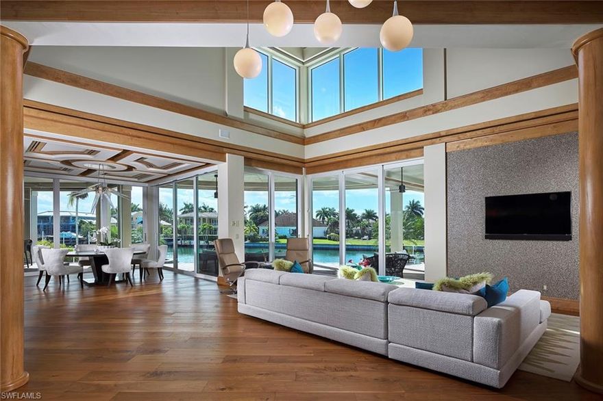 Sprawling on 165 ft of waterfrontage, this southwestern exposed gem exudes tranquility and grace. Step in through the custom mahogany front door and be greeted by the soaring ceilings of the two-story great room and sparkling water views of the bay beyond, seen through the banks of floor to ceiling glass sliders. Natural light fills the space and perfectly complements the warm earth tone motif with rich Walnut flooring, perfectly neutral wall color and a custom kitchen with luxurious Taj Mahal quartzite countertops. The modern, negative edge pool is blissfully surrounded by uncovered and covered seating areas, perfect for a day in the sun or quiet evenings by the firepit. Entertaining is effortless with the gourmet summer kitchen surrounded by a large bar countertop where guests can enjoy the best sunsets, just beyond the sparkling high rises. After a casual dinner on the lanai, hop on your boat from your private dock and take a cruise down Venetian Bay. Your Naples paradise is found.