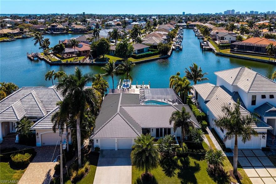 Experience elevated waterfront living on Marco Island with coveted southern exposure and breathtaking converging waterway views. This beautifully renovated 3-bedroom, 2.5-bath residence offers soaring cathedral ceilings in the living room and stunning water views from nearly every room. Walls of sliders open wide to create a seamless indoor-outdoor flow and full panoramic views, leading to an expansive lanai and pool area with multiple seating spaces designed to capture sun or shade all day. Lush professional landscaping and a newer irrigation system enhance the tropical setting. Boating enthusiasts will appreciate the newer, higher seawall and new large dock complete with sitting area, 12K boat lift, and double jet ski / kayak platform—providing effortless access to open water. Inside, hardwood style floors, a newly renovated kitchen and baths, new appliances, updated electrical panel, new rain gutters, newer two-zone house A/C, dedicated garage A/C, and a metal roof deliver coastal luxury and peace of mind. Garage doors and Wi-fi openers are new. All windows and sliders are storm rated, including a new picture window at the kitchen sink. Refined coastal design. Exceptional upgrades. Unmatched island lifestyle.
