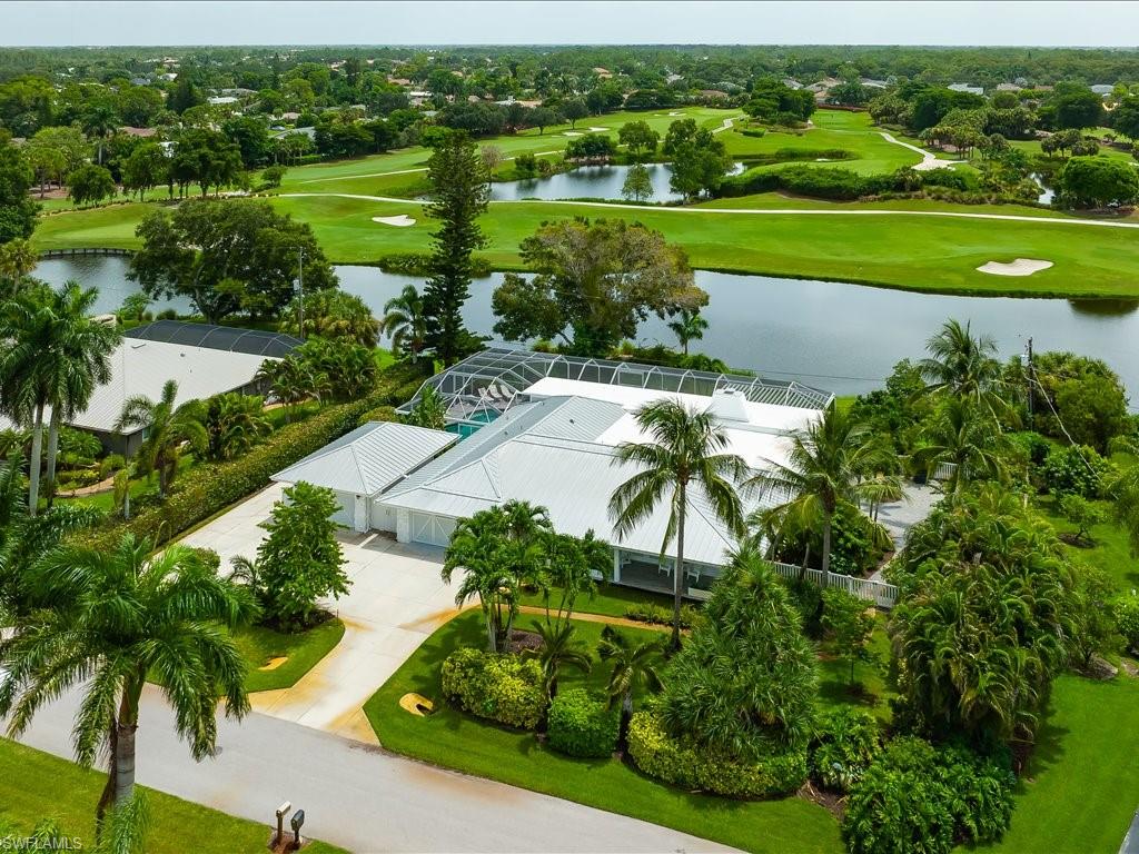Aerial view of a spacious property in Palm River Estates, featuring lush landscaping, a heated pool, and scenic lake and golf course vistas.