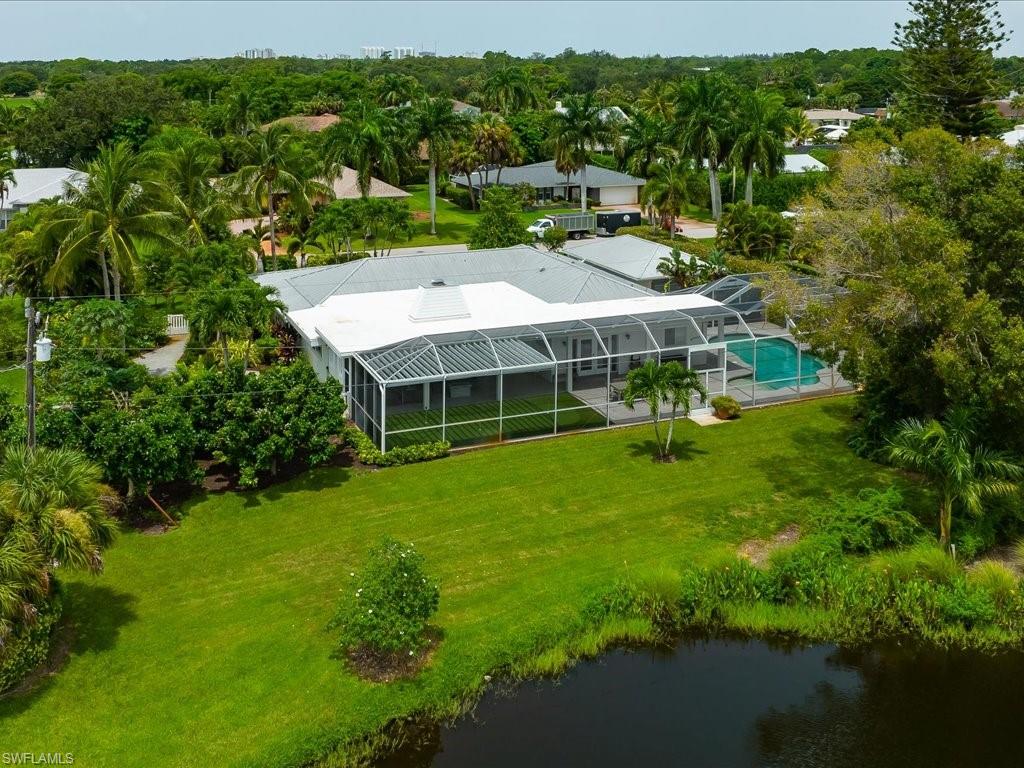 Aerial view of a spacious home in Palm River Estates, featuring a screened pool area, lush landscaping, and serene lake views, highlighting the property's outdoor living spaces and privacy.