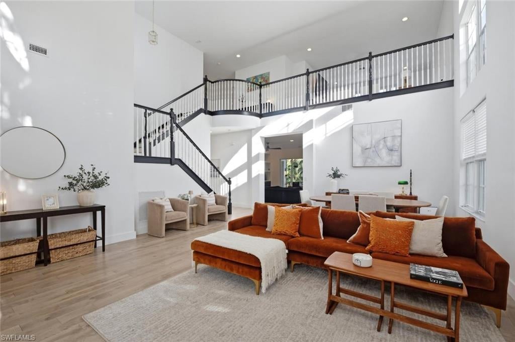 Spacious Naples living room with soaring ceilings, white oak hardwood flooring, and modern staircase in