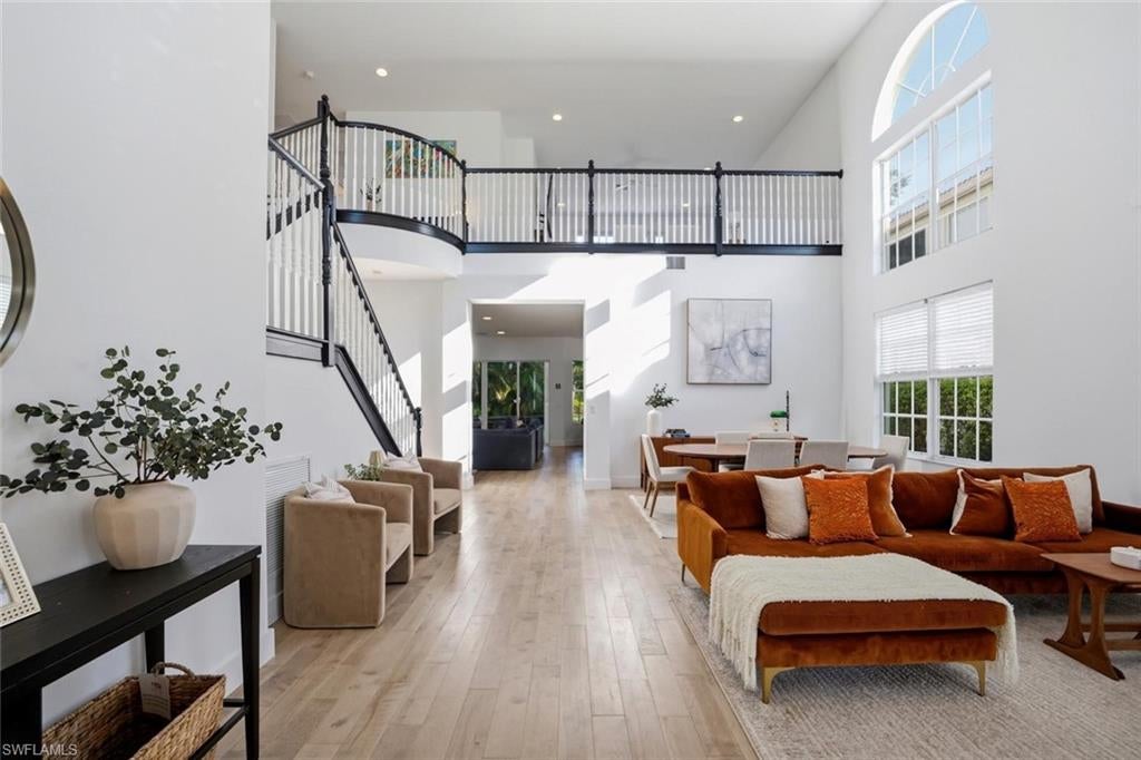 Spacious Naples living room with hardwood flooring, staircase, and waterfront views in Saturnia Lakes home.