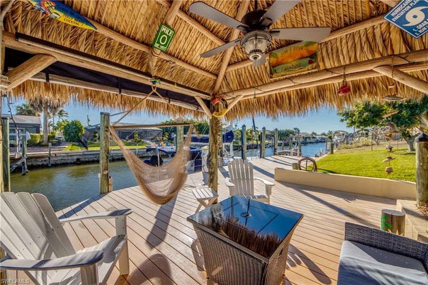 REMARKABLY BREATHTAKING. This home is defined by thoughtful curation, meticulous care, and standout detail — for the DISCERNING BUYER who knows when something special appears — YOUR MOMENT HAS ARRIVED! Perfectly positioned on a QUIET STREET near the end of a CUL-DE-SAC, THIS 3-BEDROOM, 2-BATH, 2-CAR, SAILBOAT-ACCESS HOME delivers the Florida lifestyle buyers seek but rarely find — peaceful, polished, and genuinely MOVE-IN READY. Sunshine travels throughout the home from sunrise to sunset, adding natural light through the day. The open GREAT ROOM–STYLE FLOORPLAN creates a seamless flow between living, dining, and kitchen spaces, making the home feel open, connected, and ideal for both everyday living and entertaining. The BEAUTIFULLY UPDATED KITCHEN serves as the focal point of the home and was designed with both form and function in mind. Staggered maple cabinetry with crown molding, granite countertops, stainless steel appliances, and an impressive 16’ breakfast bar create a natural gathering space. An elegant WINE BAR WITH BEVERAGE COOLER adds a refined touch. These upgrades reflect a remodel done with intention and care, including pull-out drawers, soft-close doors and drawers, a lazy Susan, and smart storage solutions.Both bathrooms have been tastefully updated. The primary bath offers a serene retreat with a white vanity, quartz countertops, a vessel sink, a towel warmer, a bidet, and a beautifully finished shower. Travertine tile and LVP flooring are complemented by custom doors, upgraded lighting and fans, plantation shutters, and fresh interior and exterior paint. Major systems are already complete, including a 2022 DIMENSIONAL SHINGLE ROOF and a 2023 HVAC.Sold TURNKEY with high-quality furnishings and décor, this is truly effortless living. Not simply furnished, but finished. No projects, no deferred maintenance, no compromises — just arrive, unpack, and settle into effortless vacation mode. The OUTDOOR LIVING SPACE is nothing short of EXCEPTIONAL. Lush, private, and magazine-worthy, the backyard offers multiple ways to unwind — from a HAMMOCK BENEATH THE TIKI HUT, to shaded lounging under the mature mango or avocado trees, to relaxing in the HOT TUB along the extended back porch as the day winds down. Set on a SAILBOAT-ACCESS CANAL with EASY ACCESS TO THE CALOOSAHATCHEE RIVER AND THE GULF OF AMERICA, this property features a TREX COMPOSITE CAPTAIN’S WALK DOCK WITH TWO BOAT SLIPS and an AUTHENTIC CHICKEE HUT — hand-built by Native Americans. A prime SW FL location close to dining, shopping, beaches, and entertainment. AFFORDABLE and TRANSFERABLE FLOOD INSURANCE at only $1,966 per year — another important detail already in place for the next owner. This is the kind of home you choose after the hard work is done — when quality matters, details matter, and time matters most. A waterfront lifestyle designed to be enjoyed, not managed. EVERYTHING about this home has a beautiful atmosphere that feels INVITING AND UNMISTAKABLY SPECIAL!