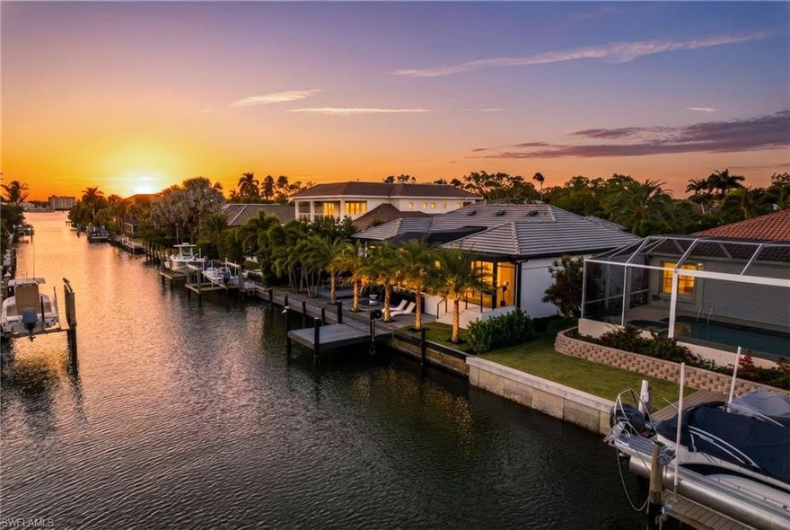 Discover an exquisite waterfront sanctuary at 1506 Jewel Box Avenue, perfectly positioned on one of Royal Harbor’s widest canals. This exceptional property offers an impressive 130 feet of total waterfrontage with two private docks and bridge-free access to Naples Bay and the Gulf waters—ideal for avid boaters seeking seamless adventures on the water.  Completely transformed into a sophisticated modern masterpiece, this 2,777-square-foot residence has never flooded and sits at 10.25 feet elevation.  It's design thoughtfully blends organic materials with cutting-edge smart technology, and every detail has been meticulously curated for beauty, functionality, and enduring value. The open living spaces feature soft hardwood floors, recessed LED lighting, upgraded interior doors, designer fixtures, and striking architectural ceiling beams.
A desirable split floor plan centers around a expansive, panoramic screened lanai with a resort-style pool, promoting effortless transitions between formal and casual living, indoor elegance, and outdoor relaxation. The gourmet kitchen is a chef’s dream, equipped with premium brushed black Samsung appliances, natural stone countertops, soft-close wood cabinetry, a generous breakfast bar, convenient recessed charging station, and subtle under-cabinet toe-kick lighting.
The luxurious primary suite serves as a private waterfront retreat, complete with serene canal views, dual walk-in closets, and a spa-inspired bathroom featuring a freestanding soaking tub, separate rain shower, dual vanities with backlit LED mirrors, and a state of the art smart toilet.
On the opposite wing, two additional bright and spacious bedrooms offer ample closet space for ultimate privacy. A versatile fourth bedroom with double French doors doubles perfectly as a home office, den, or meditation room.  The multifunctional laundry room elevates everyday convenience with custom cabinetry, a utility sink, built-in drying racks, and direct access to the climate-controlled two-car garage.
Outdoor living is equally impressive, designed for year-round enjoyment. The pool area boasts a sun shelf, integrated spa, elevated swing seating, custom dynamic lighting, and built-in fountains. A third full bathroom is conveniently tucked under the covered lounge with a built-in gas fireplace. Landscape lighting creates magical ambiance throughout the entry garden, rear deck, and docks. What truly distinguishes this home is its unparalleled boating lifestyle. The rear features an expansive Trex deck with outdoor shower, sun lounge area, swim platform and a 65-foot dock. Across the street, an additional 65-foot dock includes a 30,000-pound boat lift and protective canopy, plus four bonus parking spaces. All this awaits on a peaceful, quiet street in the prestigious Royal Harbor neighborhood—minutes from downtown Naples’ world-class dining, shopping on 5th Avenue South, and pristine Gulf beaches. Experience refined coastal living at its finest!