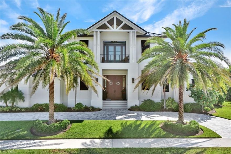 Sitting on a quiet corner within the Marco Beach enclave with direct frontage on a navigable waterway, this newer construction built by award winning R.K. Reiman Construction defines how an island residence should be lived in. Framed by royal palms, the gabled front elevation gives way to an interior defined by linear coffered ceilings that draw the eye toward the water through a wall of pocketing sliders, with wide-plank luxury vinyl flooring carried throughout. Considered the heart of the home, the kitchen is anchored by a double-waterfall edged island that could seat plenty along its working edge, with induction cooking, custom cabinetry, Sub Zero, Wolf, and Miele appliances, and a hidden pantry that absorbs the demands of entertaining without compromising the main living area. A wet bar with glass shelving and an undermount wine cooler supports the adjacent dining area. The expansive sliding glass doors give way to a covered lanai with tongue-and-groove wood ceiling that seamlessly extends the great room into a year-round living space, and is complete with a fully equipped outdoor kitchen, automatic hurricane shutters, and roll down screens.  Beyond, a heated pool, spa, and sun shelf rest on a deck framed by mature landscaping, with a pool bath. Tucked away for the utmost privacy, the ground-level primary suite places the daylight, pool, and dock within a single sequence of doors, and features dual dressing rooms, as well as a bath hosting an expansive walk-through shower and dual vanities. Additional quarters on the ground level include an en-suite guest room with lanai access and additional room currently used as a study. Upstairs, the home opens into a second living space that could be utilized as a media room, recreation room, or fitness studio, with a covered balcony commanding water views. Completing the second level, two guest suites are configured as full en-suites, each with their own view orientation and walk-in closets.  The property's deeded dock includes a boat lift, water, and electricity, with deep water access and immediate proximity to the open Gulf. Located near shopping, dining, and entertainment, including Veterans' Park, the property offers the rare convergence of tranquility and accessibility.