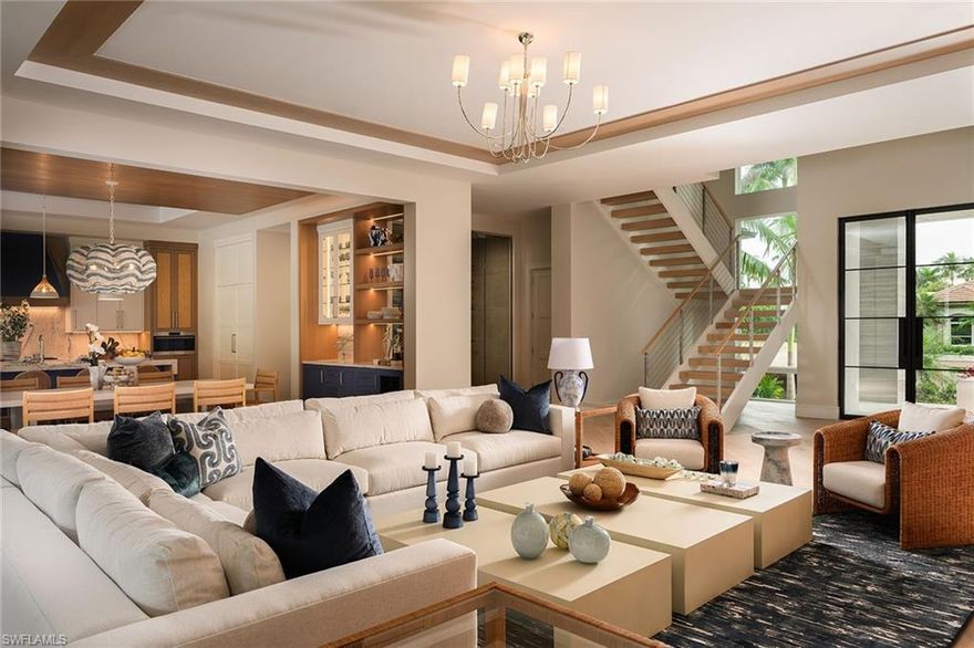 Experience the fusion of coastal sophistication and modern craftsmanship in this newly constructed estate by Diamond Custom Homes, positioned on one of the finest streets in the Moorings. With interiors and furnishings meticulously curated by Edge Interiors, this residence is more than a home—it is a statement of enduring style and seamless indoor-outdoor living. A dramatic double-height foyer and architectural floating staircase welcome you into light-filled interiors adorned with refined ceiling details and natural textures. The heart of the home is a designer kitchen featuring custom cabinetry, striking quartzite countertops, a full suite of Wolf and Sub-Zero appliances, a spacious walk-in pantry, and a dedicated wet bar with ice maker—flanked by a dramatic, glass-enclosed wine vault that becomes a showpiece in its own right. The primary suite occupies its own private wing, where morning light filters through expansive windows and bespoke details abound. Enjoy a custom morning bar, dual walk-in dressing rooms, and a spa-inspired bath finished in natural stone selections, complete with custom vanities and dual water closets. Upstairs, four beautifully appointed guest suites each feature en-suite baths and access to a private second-floor lanai—perfect for relaxed gatherings or quiet reflection. The home’s design effortlessly embraces outdoor living. Pocketing sliding doors dissolve the boundaries between interior and exterior, leading to a covered lanai with a gas fireplace, full summer kitchen with bar seating and a dedicated pool bath. A custom pool and integrated spa, framed by a gas fire pit and an expansive sun deck, create a backdrop for effortless entertaining under the Naples sky. Additional features include a private elevator, three-car garage, whole-home generator, and curated landscape design. Residents of The Moorings enjoy privileged access to the private Moorings Beach Park, as well as proximity to the waterfront shops and restaurants of Venetian Village, and the cultural charm of Olde Naples—offering an unparalleled lifestyle in one of Naples’ most prestigious coastal enclaves.