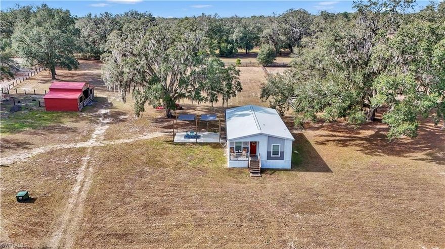 Horse-ready acreage just minutes from Ocala’s premier equestrian corridor. This 10.15-acre A-1 General Agriculture property offers cleared, fenced, high-and-dry land with beautiful mature oaks, open pastures, and excellent usability for horses, livestock, workshops, or hobby farming. The property includes a multi-stall barn with wide openings, gated paddock areas, shaded work space, and easy vehicle access.

The 2024 permitted manufactured home features 2 bedrooms plus a den/flex room, 2 bathrooms, and a bright, comfortable interior with vinyl plank flooring, modern finishes, central A/C, and a heat pump. The kitchen, living, and dining areas flow nicely, and the bedrooms offer generous natural light. The primary suite includes a double-sink vanity and oversized tile shower, while the guest bathroom offers a clean tile finish and glass shower. A dedicated laundry room with exterior door adds convenience.

Outside, enjoy a large concrete patio with shade sails—perfect for relaxing or entertaining while overlooking the pastures and oak canopy. The land has been professionally maintained: oaks carefully trimmed, fencing in place, and ample space for arenas, turnout paddocks, equipment storage, or future expansion.

Located just 6 minutes from the World Equestrian Center, with paved road frontage and NO HOA. This is an ideal setup for anyone seeking turnkey acreage in one of the nation’s fastest-growing equestrian regions.

Buyer to verify zoning uses, flood zone, utilities, and all measurements. All property information, including acreage, zoning, and legal description, is based on public records and is deemed reliable but not guaranteed.