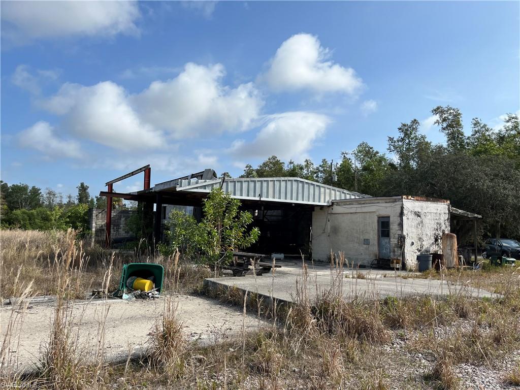Abandoned structure on land for sale at 1607 Auto Ranch RD, Naples, FL, surrounded by overgrown vegetation and open space, illustrating potential for development.