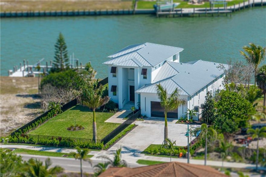 Just as you cross over the Marco Island bridge, on the left, you will see your STUNNING NEWLY BUILT (LATE 2022), FULLY FURNISHED CUSTOM HOME with INCREDIBLE WATER VIEWS & QUICK BOATING ACCESS TO THE GULF!  Located just across from the Marco Island Yacht Club where you can keep your larger yacht, this Coastal Contemporary home was designed to bring the outdoors in & to have divine wide water views within each living space. The entire main level free-flows seamlessly to the pool deck & outdoor kitchen area creating the perfect open-air entertaining spaces. The open concept kitchen features a hidden Butler's Pantry, an Italian hood, a Fusion quartzite island and white Pompei quartz back wall countertops.  You will find 2 ensuites on the lower level each with designer accent lighting, large closets & floating vanities.  Upstairs is your full span owner's suite complete with an elevator entry, sliding doors to the balcony, drop down TV & a kitchenette.  The dual vanity BR has a shower & soaking tub, entry to the large walk-in closet & there is a separated water room for privacy. Venture back down to your gorgeous glass tiled, saltwater pool to watch the sunset or share a glass of wine by your fire pit. If you enjoy an incredible water view filled with wildlife, this is truly your MOVE-IN-READY DREAM HOME right in the heart of Marco!