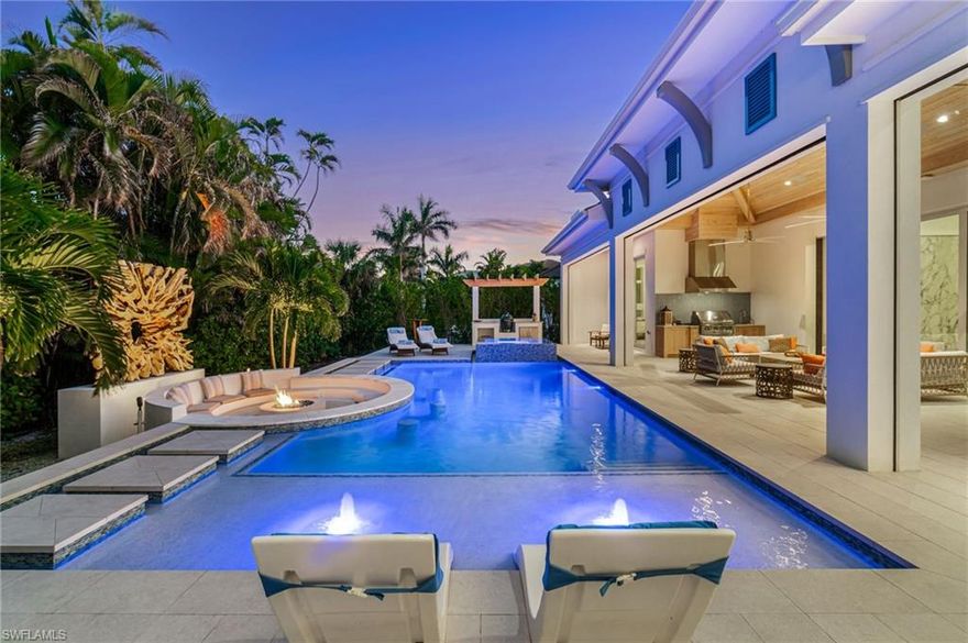 Modern Coastal Luxury Meets Biophilic Design in The Moorings — Minutes from Downtown Naples and the Beach
Experience refined coastal living in this custom Borelli-built estate home that masterfully blends modern elegance, natural elements, and indoor-outdoor living. This 4,314-square-foot single-story residence was designed with a meticulous focus on biophilic design, seamlessly connecting the beauty of nature with sophisticated architectural detail.  From the moment you enter through the grand double entry doors, your eyes are drawn through the open-concept living area to an outdoor entertainment oasis featuring a stunning 6-foot driftwood sculpture suspended over a sunken circular lounge with a fire pit and swim-up bar, flowing effortlessly into a resort-style pool and spa.
Inside, you’ll find washed oak hardwood floors, soaring detailed ceilings, and luxury finishes throughout. The open-concept floor plan connects a chef-inspired kitchen—featuring Taj Mahal quartzite countertops, Sub-Zero and Wolf appliances, custom wood cabinetry, and a walnut wet bar—to elegant living and dining spaces perfect for both intimate gatherings and grand entertaining. This 4-bedroom + office + media OR 5 bedroom + den/flex room residence includes five full designer bathrooms. The media room with its custom built-in bar creates a stylish retreat for movies or game nights.
The primary suite is a true sanctuary, offering dual custom walk-in closets, a soaking tub, oversized walk-in shower with dual shower heads, and two private water closets.  Designed for the Naples lifestyle, the outdoor living area extends over 650 sq. ft. of covered space and includes a summer kitchen with grill and Green Egg station, electric roll-down screens, outdoor shower, and a fully fenced backyard surrounded by mature tropical landscaping. The southeast rear exposure ensures ideal sunshine over the pool during winter months.
Additional upgrades include:
 • Crestron smart home automation
        • Generator (on order)
 • Integrated security and sound system
 • Two tankless water heaters
 • Electric roll down hurricane shutters
 • Split three-car garage with epoxy floors

Located just minutes from 5th Avenue South, 3rd Street South, and Naples’ white sand beaches, this home offers private beach access through the optional Moorings Beach Park Association. Enjoy an unparalleled Naples lifestyle—morning walks on the beach, afternoons by the pool, and evenings dining in the heart of downtown. Whether you’re seeking a second home in Naples or planning a full-time relocation from the Midwest or Northeast, this residence delivers the perfect balance of sophistication, comfort, and coastal serenity.