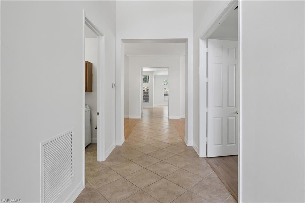 Spacious interior hallway with tile flooring and open floor plan in Saturnia Lakes home.