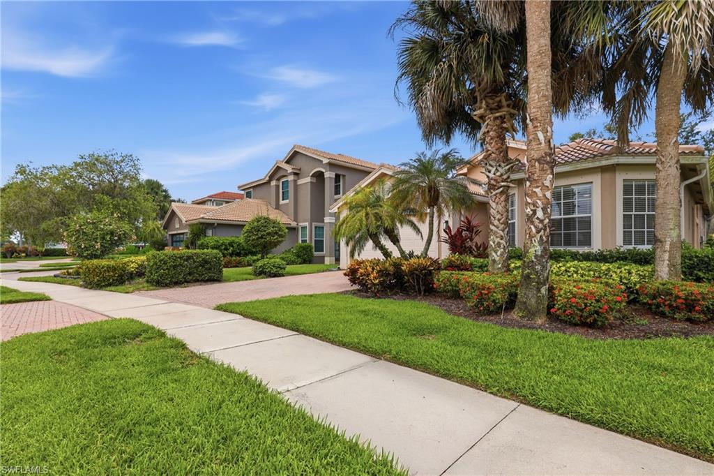 Spacious home in Saturnia Lakes, North Naples, Florida, with palm trees and landscaped yard.