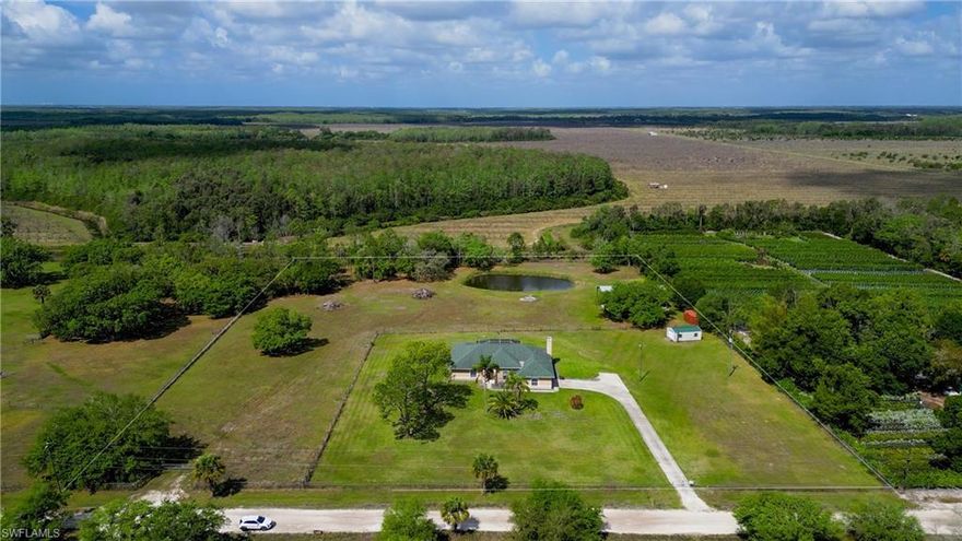 Places like this are disappearing fast in SWFL. Your private Florida retreat is here where dirt roads, crickets, and birds replace the noise of the city, and stress from the hustle and bustle of life fades as you open up your gate and pull up to the side-entry 2-car garage. A pool home with 3 bedrooms, 2.5 baths with 2,490 sqft of living space on 5.49 pristine acres. The Entire parcel is fully fenced in with one enclosure around the main home with an outbuilding equipped with a separate 200 Amp Service, and water Hook up for RV Parking. Second enclosure has approximately 3.75-acres of pasture separately fenced and a Huge 60'x40' Pole barn and private pond backing up to a private preserve. Providing an ideal space for animals, equipment, toys, or any outdoor hobby you may have. Tall French doors welcome you into a stunning formal dining area with soaring 12 ft ceilings. This open-concept floor plan is filled with plenty of natural light as you walk from the formal dining area into the living and dining area. There will be plenty of holidays and memories to be enjoyed fireside next to your fireplace lined with Riverstone rock adding to that feeling of warmth, comfort and a place to call home. You can't have the perfect house without a huge kitchen built for the avid cook with plenty of counter space, bar-height seating, stainless steel appliances, and an electric cooktop. Even your guests or family will be comfortable in oversized guest bedrooms and an exceptionally large guest bathroom with dual sinks. The owner’s suite is a true retreat, with French door entry and another set out to the lanai. The owner's suite matches the theme being oversized with a large soaking tub, walk-in shower, and a giant walk-in closet. Outdoor living shines with five separate exits to the huge covered back lanai—from the living room, formal dining room, owner’s suite, dining nook, and hallway near the powder room—creating an easy indoor-outdoor flow. The covered lanai offers plenty of room to escape from the heat or weather and includes a sink and counter space within a screened enclosure that wraps around the electric-heated pool. Watching evening sunsets over the true old Florida backdrop or a weekend entertaining, this property combines space, comfort, and a peaceful country lifestyle, all within a reasonable drive of Fort Myers conveniences located at the end of corkscrew between SR-82.