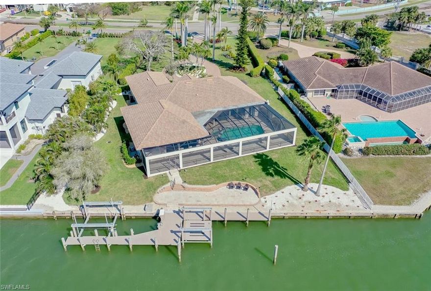 This stunning house, custom built by Slocum and Christian, is an expanded version of their highly sought-after Emerald Bay floorplan. Renovated in 2012, it boasts an outstanding layout that seamlessly combines spacious indoor and outdoor areas, making it perfect for entertaining. Impressive features include impact sliding doors for abundant natural light, soaring high ceilings, and custom built-ins for entertainment, workspaces, and a bar. The large screened lanai offers a captivating outdoor lifestyle, complete with a grill and bar, casual dining area, swimming pool, spa, full bathroom, and both covered and uncovered relaxation spaces. Additionally, the property features a 95' dock with two boat slips and lifts, as well as an outdoor patio. With nearly one acre direct gulf access homesite, there's potential to expand if desired. If you have a discerning eye for design and a desire to take it to the next level, this exceptional property awaits.