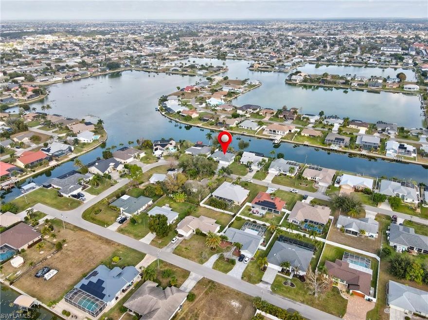 Waterfront Pool Home | 3 Bed + 2 Bath + 3 Car Garage | Wide Water Views | Rhodes Canal & Shamrock Lake. ***NO FLOOD INSURANCE REQUIRED*** This home is conveniently located in the CENTER OF THE CITY! Exceptional opportunity to own a beautifully maintained waterfront HEATED pool home in SE Cape Coral offering expansive wide water views of the Rhodes Canal and Shamrock Lake. This 3 bedroom, 2 bathroom home with a 3-car garage is located in a quiet, hidden gem neighborhood with only one road in and out, surrounded by water — providing added privacy and limited through traffic. The exterior of this home features a screened front entry with double door entrance, mature tropical landscaping with decorative concrete curbing, fenced backyard, and concrete cantilever dock and more! Dimensional Shingle Roof only 3 years old (replaced after IAN). Interior highlights include: • Updated kitchen with granite countertops • Upgraded white cabinetry with crown molding & modern hardware • Stainless steel appliances • Cabinet pantry • Brick-look tile backsplash • Drop pendant lighting • Newer wood laminate flooring (original tile remains underneath for buyer preference) • Plantation shutters throughout, including rear sliders • In-residence laundry room with utility sink. The split floor plan offers a spacious primary suite with tray ceiling, large walk-in closet, and double door sliders leading to the oversized under-truss lanai and pool area. Guest bathroom has been upgraded with tile flooring, upgraded vanity, custom mirror, and floor-to-ceiling tiled shower with frameless bypass glass doors and natural light window. Outdoor living out back is designed for entertaining with a large covered lanai, private pool, Kevlar roll-down hurricane shutters on the lanai (for sun blocking and added privacy, functioning sprinkler system, and WIDE water views. Located near shopping, dining, schools, and easy access to Fort Myers. Waterfront + pool + 3-car garage + wide water views — a rare combination in this area.