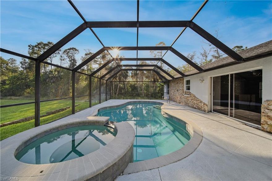 Your own private oasis in Naples. Located on 1.59 acres in Golden Gate Estates, this beautifully updated 4-bedroom, 2-bath home offers space, privacy, and modern comfort with no HOA restrictions. The open-concept floor plan is filled with natural light and features vaulted ceilings and wood-plank tile flooring throughout. The kitchen has been upgraded with granite countertops, stainless steel appliances, and wood cabinetry, while both bathrooms have been fully remodeled. Step outside to a spacious screened lanai with a private pool and spa, ideal for relaxing or entertaining, enhanced by desirable southern exposure and lush surroundings. Situated in a non-flood zone with ample room for future additions such as a guest house, workshop, or RV and boat storage, this property offers a rare opportunity to own acreage living with convenient access to everything Naples offers.