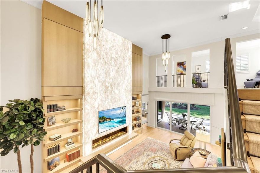 A rare and refined masterpiece nestled within one of North Naples most sought after communities. This extraordinary residence is the result of an inspired vision brought to life through meticulous craftsmanship and uncompromising attention to detail. From the moment you enter, the home makes a striking impression anchored by a dramatic 19 foot, floor-to-ceiling backlit Crystallo Quartz feature wall that serves as a stunning work of art. Soft illumination radiates through the quartz, creating a warm, inviting ambiance that elevates the great room into an unforgettable living experience. At its base, an Aquafire electric fireplace delivers the beauty of dancing flames, adding both drama and serenity. Solid white oak floors flow seamlessly throughout, complemented by custom millwork, refined crown molding, and carefully curated designer lighting most notably the double cut-crystal and bronze Jonathan Browning chandeliers in the Great Room. The kitchen is a true showpiece, featuring premium Taj Mahal quartz countertops, custom cabinetry with illuminated glass display accents, a professional-grade GE Profile appliance suite, double ovens, and a thoughtfully designed pantry. Custom built-in pull-out shelves and hidden slide-out spice organizers further enhance both form and function. Motorized Conrad Grass Shades, among the finest available, adorn the FIRST FLOOR primary bedroom, great room, and breakfast room sliders, providing effortless light control and refined texture. The home’s thoughtful design continues upstairs, where a grand executive office addition offers cathedral ceilings, Apex windows, and extraordinary natural light creating an inspiring space for work, a creative retreat or second master suite. A private elevator, discreetly integrated into the home, ensures effortless access to the second floor and enhances long-term livability. Each Bathroom throughout the home reflect a refined, spa-like aesthetic, showcasing natural stone finishes, custom floating cabinetry, frameless glass showers, elevated designer fixtures, and a Venetian plaster finished powder bath. Recent enhancements bring peace of mind and modern convenience, including a 32kW Generac whole-house generator, a 1,000-gallon propane tank, New tile roof, fresh exterior paint, and an integrated security camera system. Set within the lush, gated surroundings of Autumn Woods, residents enjoy mature landscaping, scenic walking paths, tennis and pickleball courts, resort style community pool, clubhouse amenities, all within close proximity to Naples’ renowned beaches, dining, and shopping offering an unmatched lifestyle of elegance and ease. Rarely does a home of this caliber, craftsmanship, and location become available an extraordinary opportunity to own a timeless masterpiece in the heart of North Naples. Schedule your private tour today!