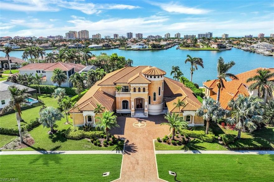 Custom-built bayfront residence in Marco Island's prestigious Estates section with nightly sunset views. This 5-bedroom, 7-bath masterpiece showcases remarkable architecture and a whole-house generator. Enter through a 2-story cupola foyer with elegant appointments gracing every corner. The open living areas boast a statement fireplace, tray ceiling, and Gourmet Chef's kitchen with double islands, custom gas range, breakfast bar and  dining area overlooking the pool and bay with formal dining room nearby. An opulent ground level primary suite features a stunning custom bath, built-in closets, wood-lined study with a 2nd ensuite bedroom. Featuring a grand home theater, butler's pantry, oversized laundry with pet wash station and stalls, and three generous en suite bedrooms on the second level with shared lanai. Indoor/outdoor living from sprawling retractable screened/storm shuttered lanai with chef's kitchen, lounging, sitting, dining areas; pool, spa and sand beach make this an entertainer's dream along with a pair of 2-car air-conditioned garages with 2 charging outlets each. Enjoy wide water views and phenomenal sunsets over Smokehouse Creek and direct access to Gulf waters.