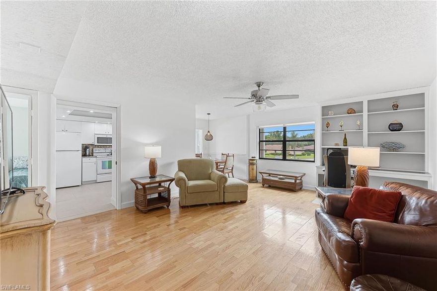 Who says living the Naples lifestyle has to cost a fortune? This bright and beautifully maintained 2-bedroom, 2-bath corner-unit condo offers an incredible opportunity to live near the Gulf beaches and iconic Fifth Avenue South for under $180,000.  Everyone knows condo prices have softened, creating opportunity for savvy buyers, and this residence has been strategically priced to reflect today’s market realities — making it a true SELLER'S LOSS and BUYER'S GAIN!  Flooded with natural light from multiple exposures and impact glass windows, this second-floor turnkey furnished residence is move-in ready — just bring your toothbrush. Warm hardwood flooring welcomes you into the inviting living room featuring a built-in desk and bookshelves, while the adjoining kitchen offers granite countertops and sweeping views of the beautifully maintained community landscaping.  The elevated second-floor location provides peaceful views and added privacy, with the elevator conveniently located just steps from the front door. Nearly every room enjoys exterior natural light, creating a bright and cheerful atmosphere throughout.  The spacious primary suite features exceptional closet space and a recently renovated bath with tiled shower. The guest bath has also been tastefully updated with a new vanity and tub. A dedicated interior laundry room with washer and dryer adds everyday convenience.  Additional highlights include a covered carport parking space, separate exterior storage, and easy access to the community pool and hot tub just steps away.  Opportunity knocks...will you answer?