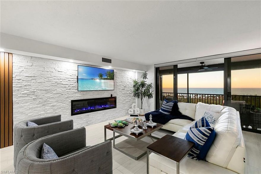 Redesigned in 2021, this turnkey corner residence offers 1,480 square feet of elevated coastal living in a premier Vanderbilt Beach community. The end-unit layout features a wraparound screened lanai, accessible from the main living area and primary bedroom, with porcelain tile flooring throughout. The open kitchen includes a Blue Bahia Brazilian granite island, quartz countertops, premium appliances and a wine cooler. Architectural wood slat and stone feature walls, a fireplace and battery-operated shades enhance the interiors. Two bedrooms, two baths, glass shower enclosures, custom closets and quartz vanities provide comfort and functionality. Storm protection includes impact-resistant sliders and windows, plus remote-controlled aluminum shutters. Additional features include Trane air conditioning, updated water heater, three TVs and three lanai fans. Offered turnkey, including bedding and kitchenware. Amenities include a renovated lobby, fitness center, assigned covered parking, guest parking.
