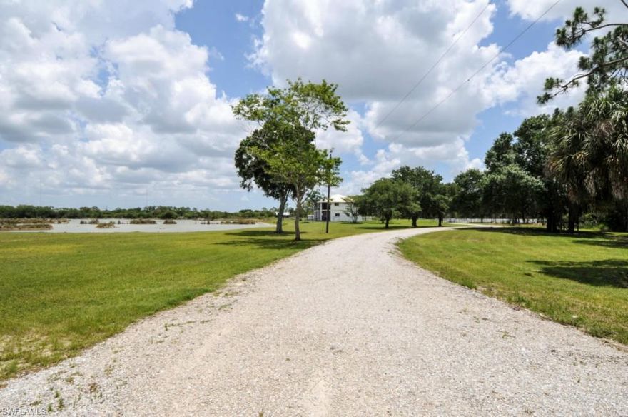 North Ft. Myers-At the end of the pavement lies a very unique country estate.  As you enter the driveway, you will be struck by the expanse of water on the private 75 acre lake.  This house and property is on 10 acres and the adjoining 10 acres which is a separate parcel is being sold as a total package. Parcel 422532100003 known as OhanaHale, LLC adjoins and is sold with this property.  The home was built in 2004 and has been extensively renovated since 2011. It is a 2 story plantation style home with two porches running the full 60 feet of the home.  The upper lanai has been enclosed with sliders and screens while the first floor lanai is fully screened.  There is tile throughout the main living area, a soaring 20 foot ceiling in the living and dining area and a stone fireplace with cypress mantel.  The kitchen is large and has plenty of cabinets with level 4 granite, new appliances, wine cooler, lighted cabinets for crystal. There is one bedroom, office,full bath 1st floor.  There are 3 bedrooms, 2 baths on the second level with a large loft area which is open to the first floor.  There are 2 out sheds and a 30x40 barn for horses, etc. Attached description of the property.