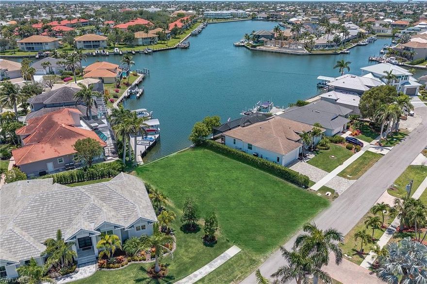Discover the setting for your dream home on this exceptional waterfront home site, offering tranquil southeastern exposure and stunning wide water views. On a quiet cul-de-sac street in one of Marco Island’s desirable and central neighborhoods, this peaceful retreat is surrounded by newer luxury homes and offers easy boating access to the Gulf. Enjoy a scenic boat ride from your backyard through the updated Collier Bridge with approximately 14-foot clearance, and picturesque waterways of Smokehouse Bay and Collier Bay, past the vibrant Esplanade Shoppes, home to waterfront dining, ice cream and charming boutiques, and on to open waters of the Marco River and Gulf. Watch dolphins and manatees glide by, explore Keewaydin Island and nearby uninhabited islands, or spend your days fishing, shelling, paddleboarding and kayaking in paradise. This 80x110x80x110, 8,712-square-foot-wide water view lot features an existing seawall ready to accommodate a 24-foot boat and dock and provides ample room for a custom-designed home tailored to your lifestyle. Architectural floor plans, elevation drawings, renderings, and a custom dock plan are available to streamline your vision and building process. This homesite is conveniently near Marco Island Yacht Club, local marinas and an array of island amenities. Just minutes away, you’ll find upscale and casual dining, boutique shopping, entertainment, and cultural experiences at the art center and museum. Stay active with nearby tennis and pickleball facilities, a fitness center and championship golf courses. For family fun and recreation, Veterans Park and Mackle Park are close by. Best of all, you're just a short drive or bike ride to award-winning Residents’ Beach, known for its pristine white sand, gentle waves and wide crescent-shaped shoreline, ideal for sunbathing, relaxing, beach yoga, barbecues and seasonal events. Executive airport is just a few minutes' drive from the island. Whether you're ready to break ground now or planning for the future, this rare offering presents the ultimate opportunity to create a custom coastal retreat in a premier location. Don’t miss your chance to build your island dream home with peaceful water views, superb boating and best of Marco Island at your fingertips.