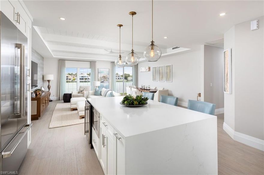 Sunrise over Venetian Bay and sunset over the Gulf, experience both from this beautifully reimagined coastal retreat at Venetian Villas in Park Shore. Located on the second floor and offering 2,479 total square feet of thoughtfully designed single-level living, this residence blends bespoke craftsmanship with relaxed coastal elegance. A private elevator opens directly into light-filled interiors featuring wide-plank tile flooring both elegant and pet friendly enhancing the home's sophisticated yet comfortable coastal aesthetic and refined finishes throughout. The elevated living space provides added peace of mind, with approximately 95% of the residence unaffected during past storms.
The expansive great room flows seamlessly into the formal dining area, creating an inviting space for both everyday living and effortless entertaining. At the heart of the home, the gourmet kitchen showcases a striking stone-wrapped island, premium appliances, wine storage, and exceptional design that balances beauty and functionality.
The well-designed floor plan offers three spacious ensuite bedrooms plus a powder room, providing privacy and comfort for both residents and guests.  Additional features include a tucked away laundry area, custom finishes, soft drapes, privacy shades, and a private garage for one car.  
The spacious balcony, with motorized awning, is ideal for enjoying coffee while taking in the bay breezes and wide water views.  Watch stunning sunsets through the home's unique curved windows that look out over the marina and toward the Gulf.  Just across the street, residents enjoy direct beach access along the Gulf, including private Park Shore beach privileges, making it easy to start the day with a peaceful walk along the shoreline or an energizing morning stroll along the scenic beachfront paths, a favorite daily ritual among neighbors. Venetian Villas offers a bayside pool, secure entry, excellent onsite management, and potential boat dock availability.  An exceptional opportunity to experience luxury, panoramic water views, beach access, and effortless coastal living in one of Naples' most desirable waterfront locations.